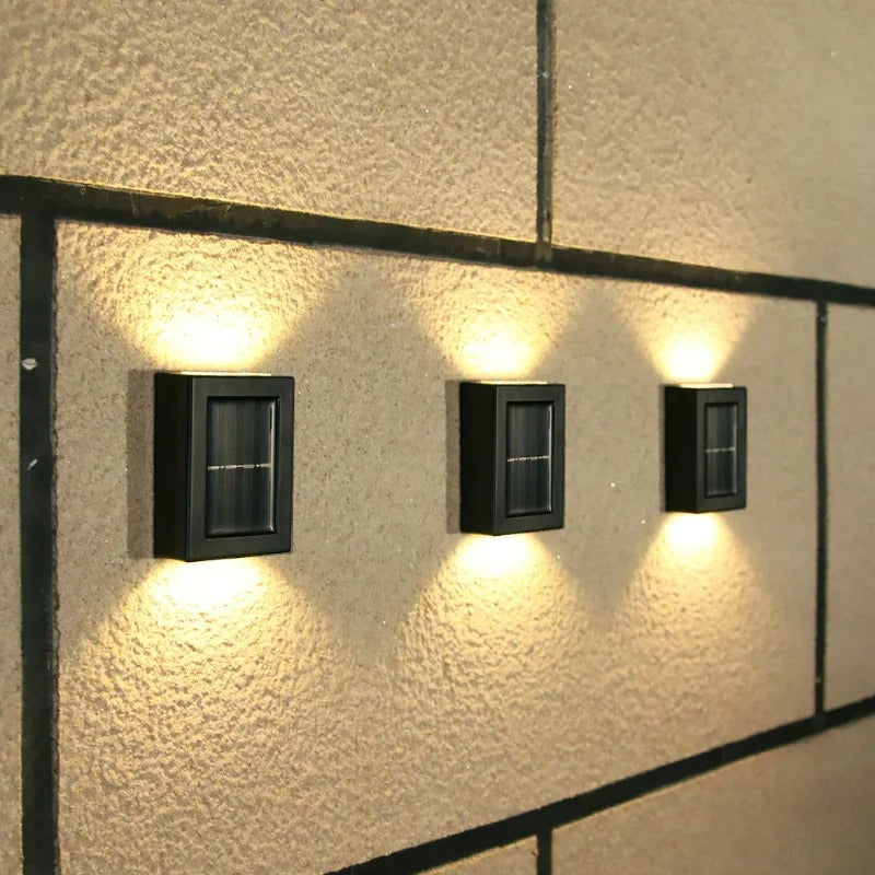 Drei schwarze Solarleuchten an Wand, energiesparend, modern, Außenbeleuchtung, LED.