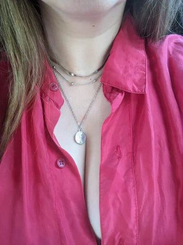Rote Bluse, silberne Halskette mit Anhänger, Damenmode, eleganter Stil, Nahaufnahme.