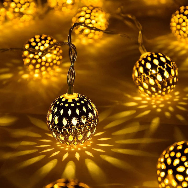 "Solarbetriebene Lichterkette mit marokkanischen, warmweiß leuchtenden Metallkugeln, ideal für die Gartenbeleuchtung."