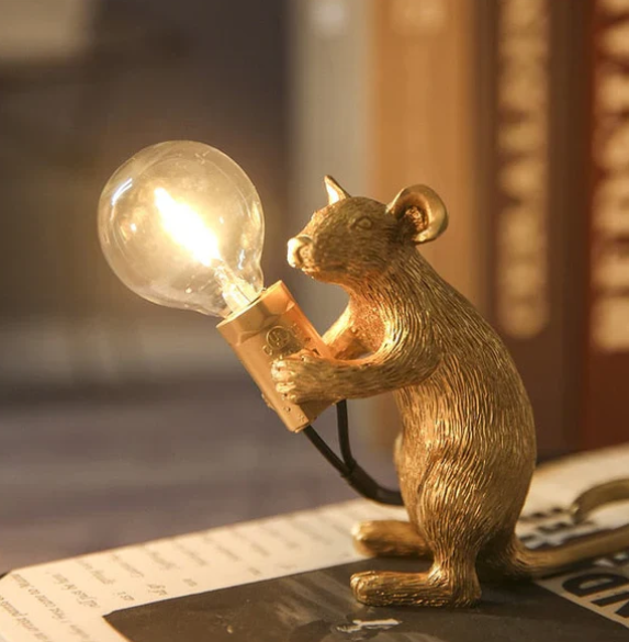"Weiße Maus Tischleuchte in sitzender Position, strahlt warmes Licht, ideal für stilvolle Wohn- oder Schlafräume."