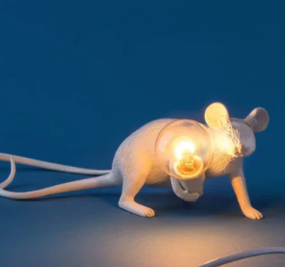 "Weiße Maus Tischleuchte in sitzender Position, strahlt warmes Licht, ideal für stilvolle Wohn- oder Schlafräume."